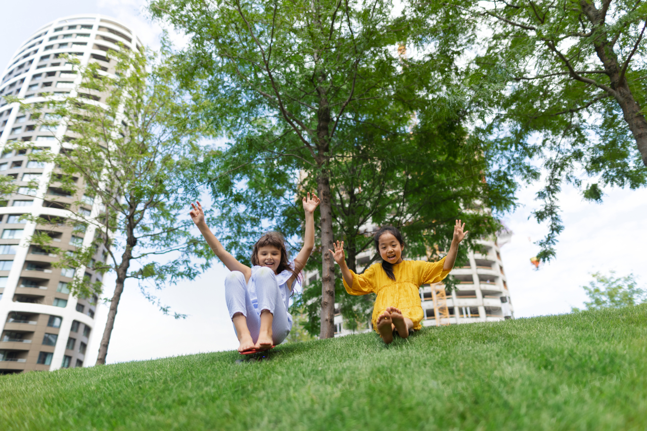 Asian girl trying to skateboarding with her friend in a city park, active kids concept.