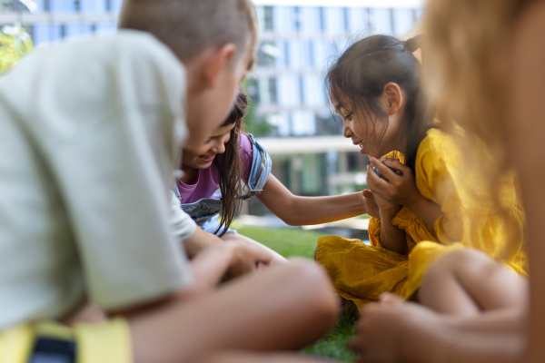 Happy kids playing and talking together in s city park, during summer day.