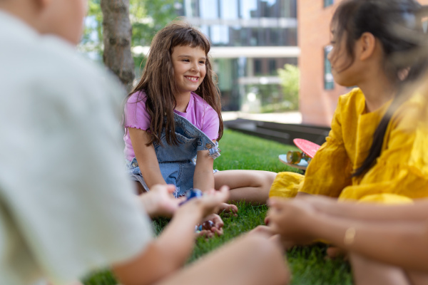 Happy kids playing and talking together in s city park, during summer day.