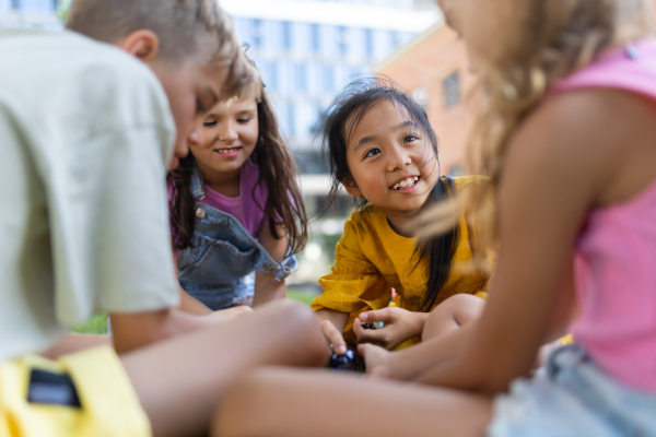 Happy kids playing and talking together in s city park, during summer day.