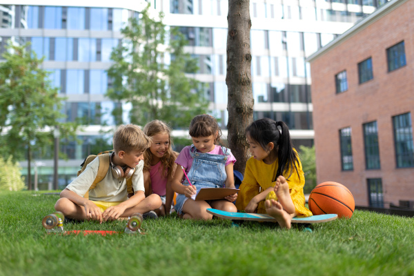 Happy kids playing and talking together in s city park, during summer day.