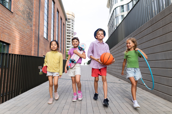 Happy kids playing and talking together in s city, during summer day. Looking at camera, low angle view.