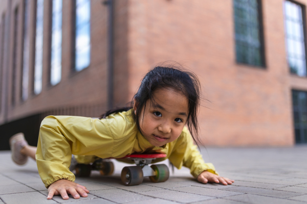 Little asian girl having fun on a skateboard.