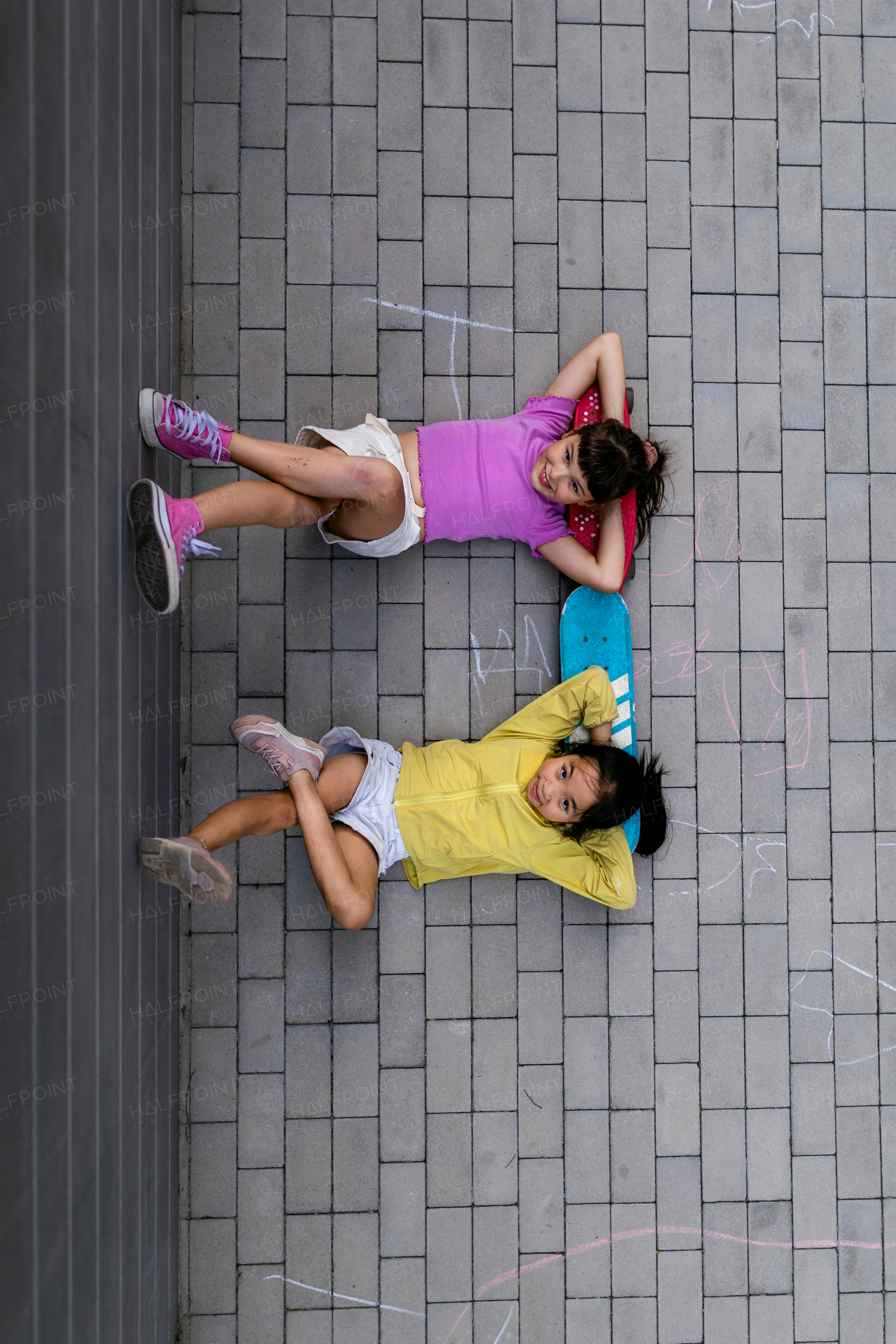 Happy friends lying in sidewalk, resting after skateboarding. Top view.