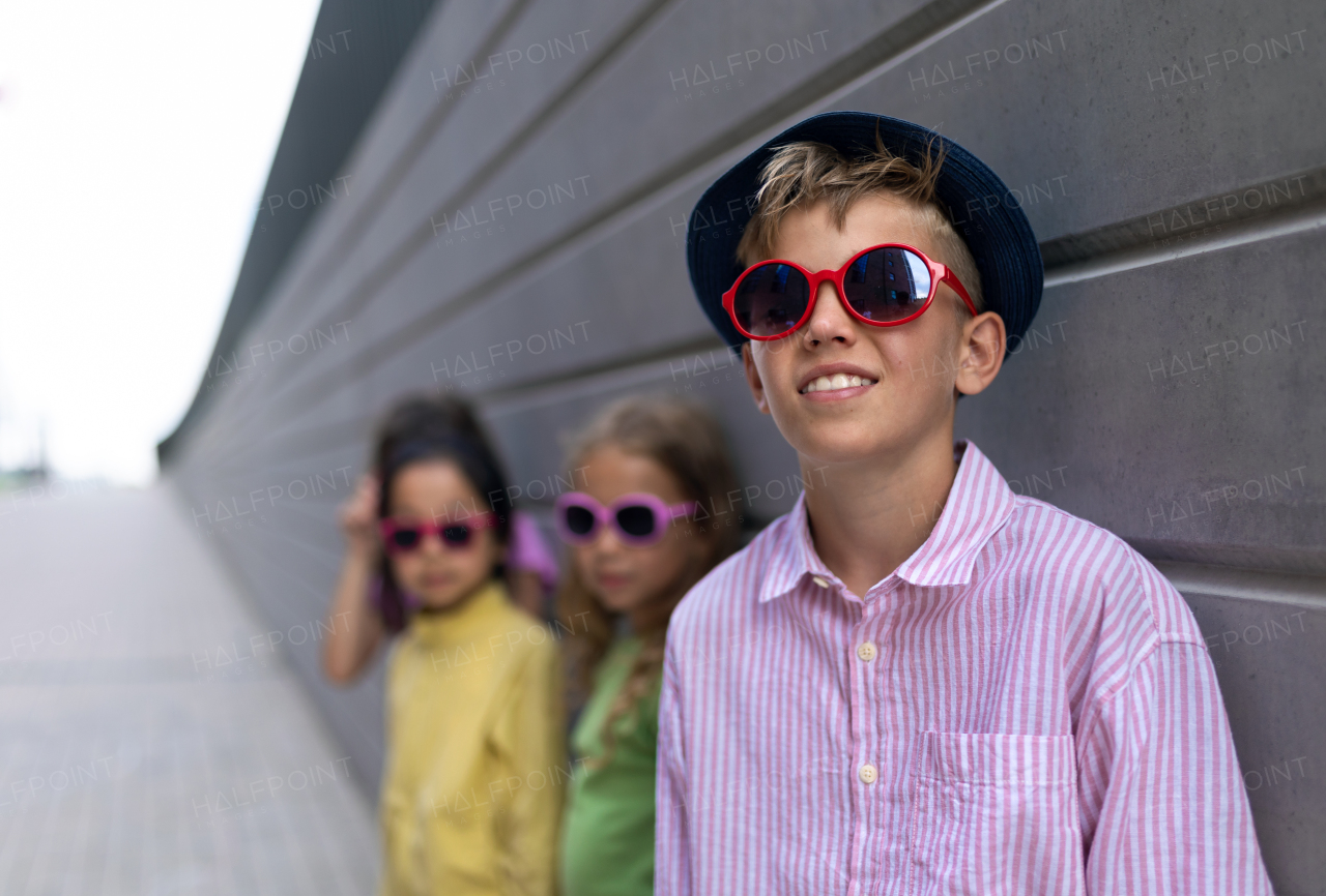 Happy friends posing together in city, standing in front of a concrete wall and looking at camera.