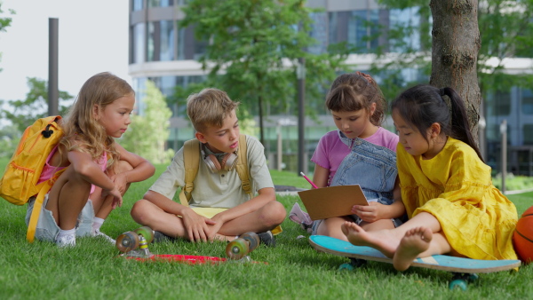 Happy kids playing and talking together in s city park, during summer day.