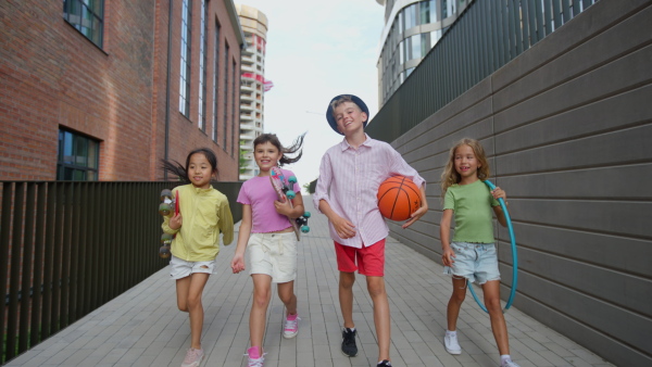 Happy kids playing and talking together in s city, during summer day. Looking at camera, low angle view.