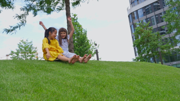 Asian girl trying to skateboarding with her friend in a city park, active kids concept.