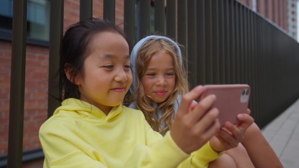 Happy children, friends, taking selfie in a city.