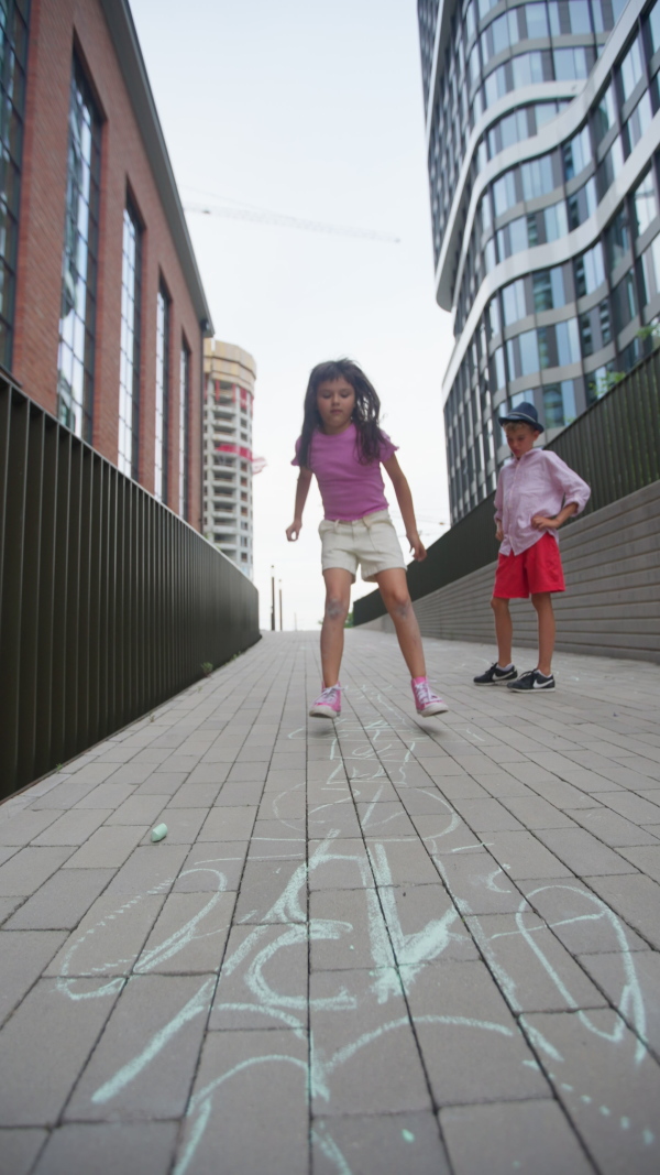 Two kids playing jumping game in the city. Vertical footage.