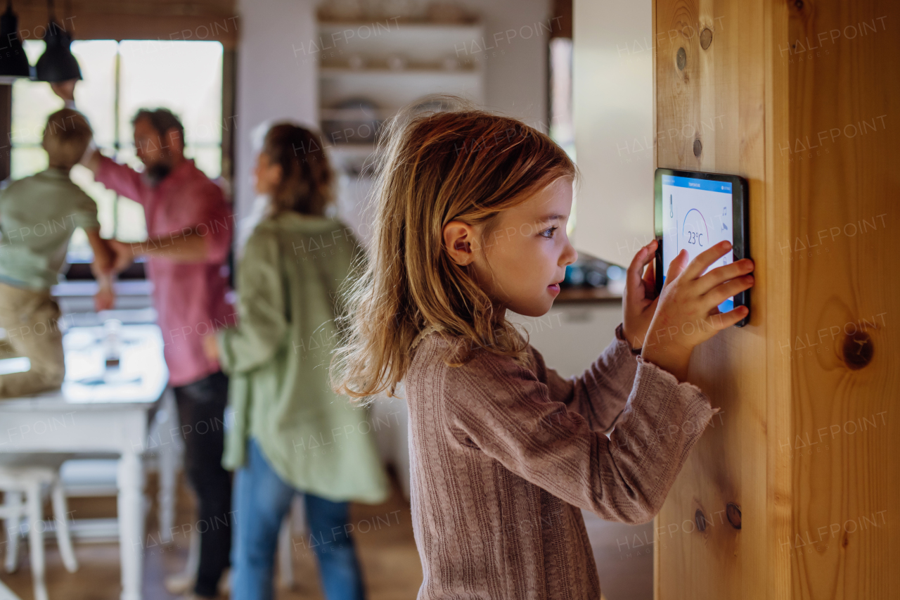 Girl looking at the smart thermostat at home, checking heating temperature. Concept of sustainable, efficient, and smart technology in home heating and thermostats.