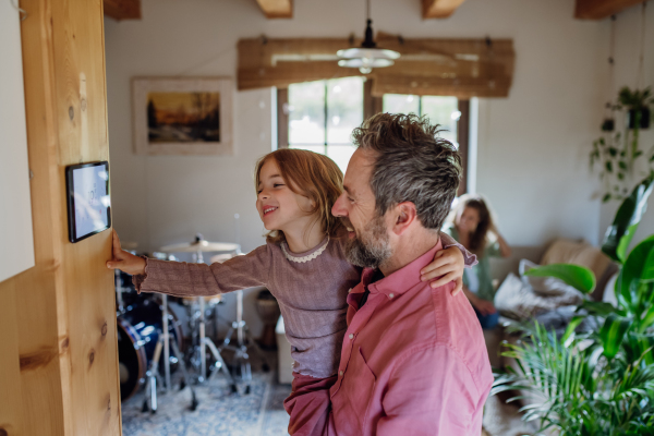 Little girl helping father to adjust, lower heating temperature on thermostat. Concept of sustainable, efficient, and smart technology in home heating and thermostats.