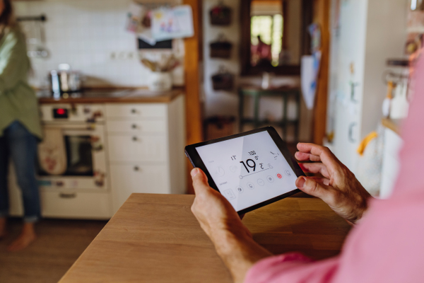 Father using smart thermostat, adjusting or lowering heating temperatures at home. Concept of sustainable, efficient, and smart technology in home heating and thermostats.