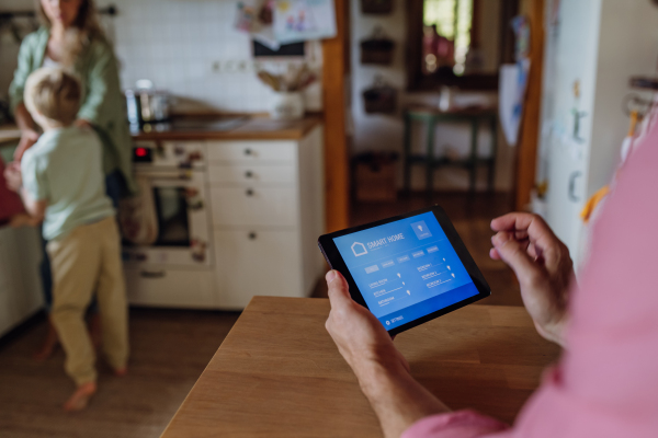 Father using smart thermostat, adjusting or lowering heating temperatures at home. Concept of sustainable, efficient, and smart technology in home heating and thermostats.