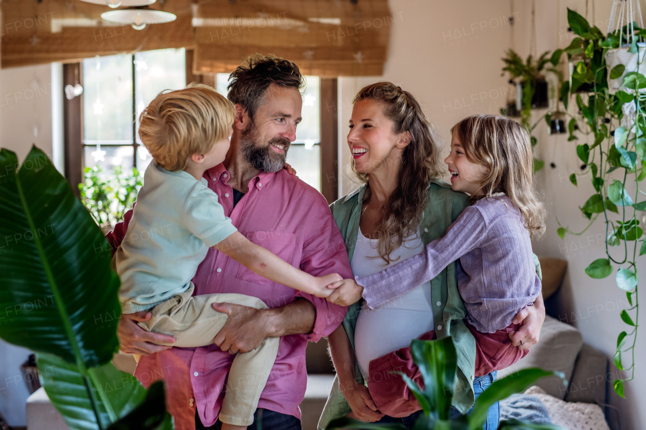 Portrait of young family at home. Pregnant mother with her children and husband in the living room.