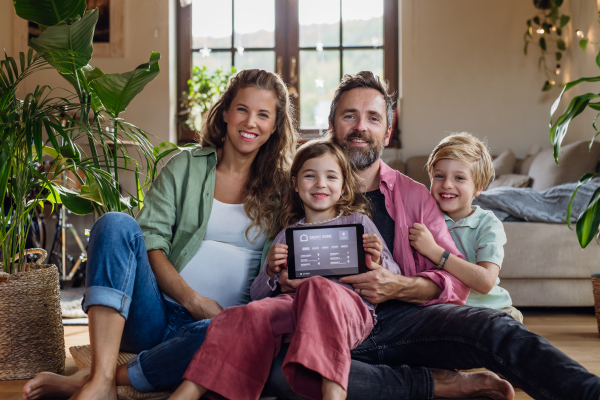 Family holding smart thermostat, adjusting or lowering heating temperatures at home. Concept of sustainable, efficient, and smart technology in home heating and thermostats.