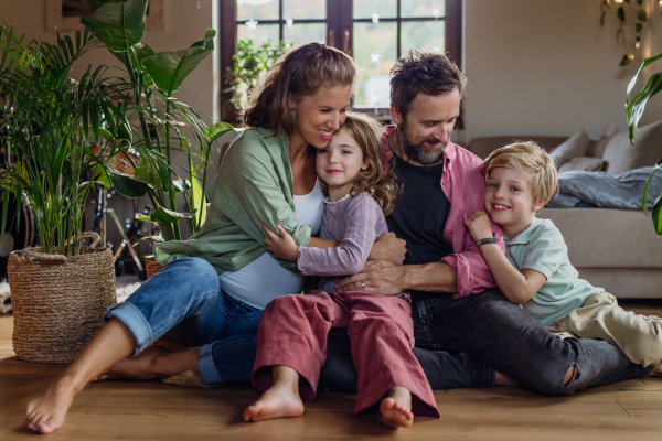 Portrait of young family at home. Pregnant mother with her children and husband in the living room.