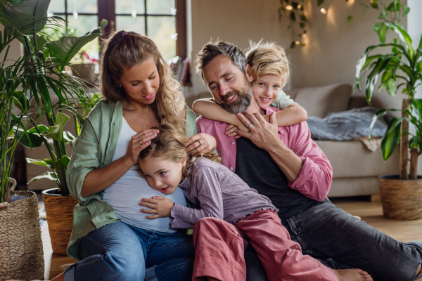 Portrait of young family at home. Pregnant mother with her children and husband in the living room.