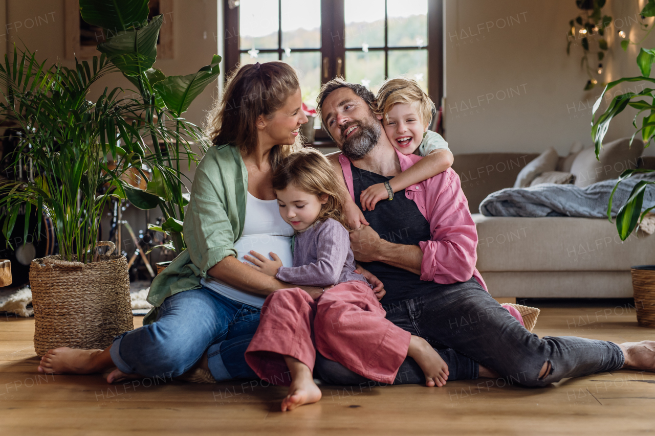 Portrait of young family at home. Pregnant mother with her children and husband in the living room.