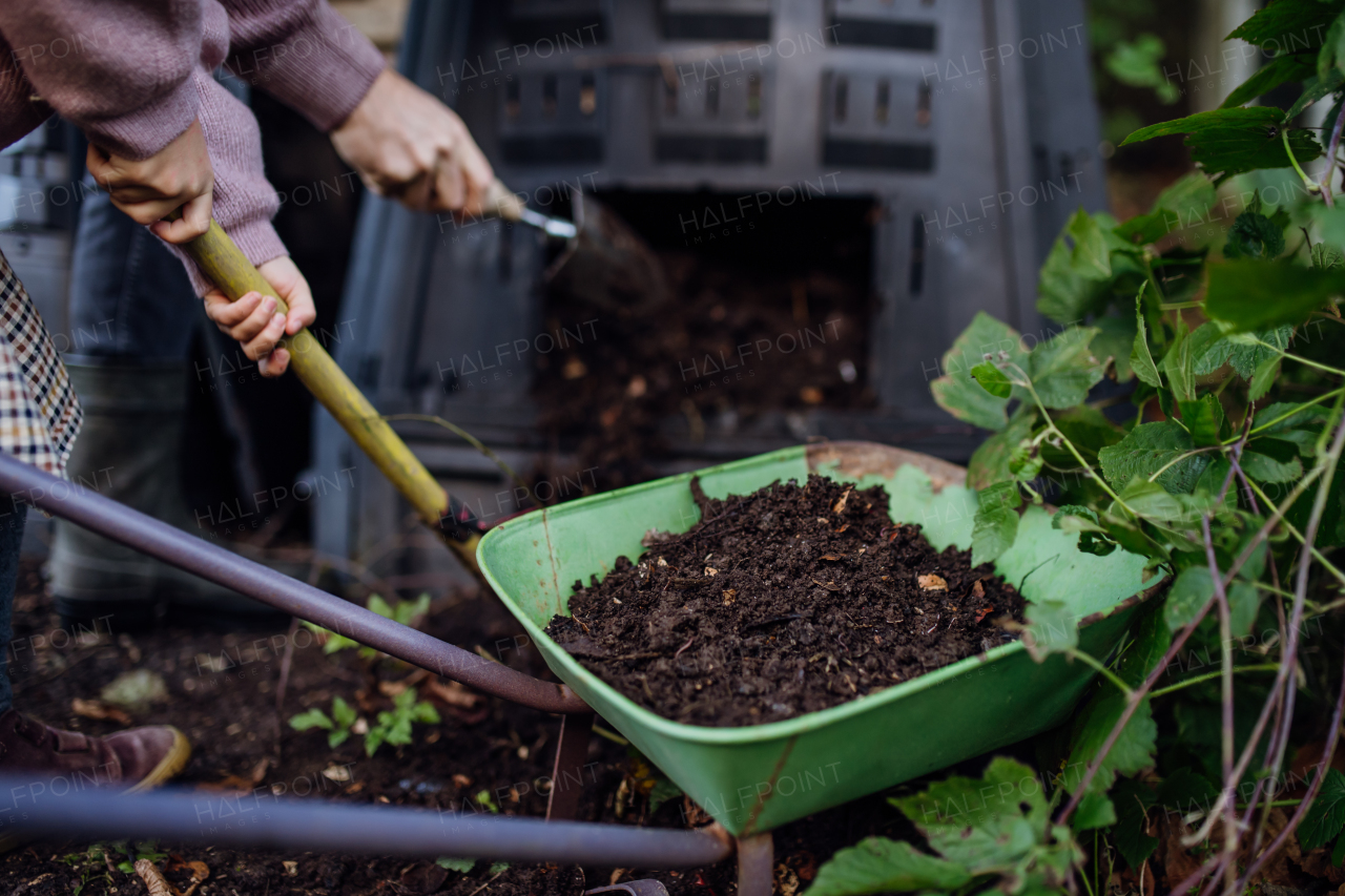 Removing compost from the composter in the garden. Concept of composting and sustainable organic gardening.