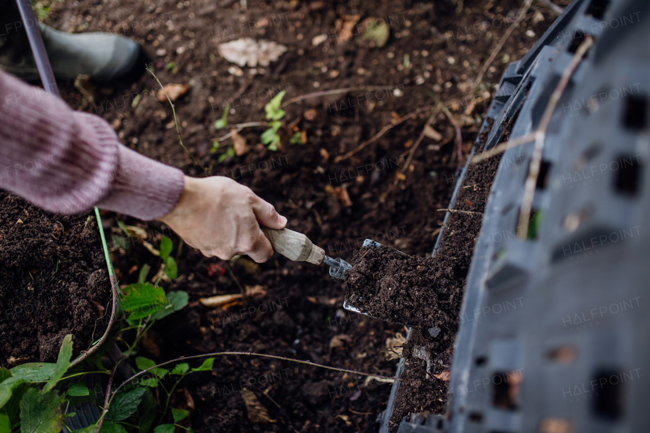 Girl removing compost from a composter in garden. Concept of composting and sustainable organic gardening.