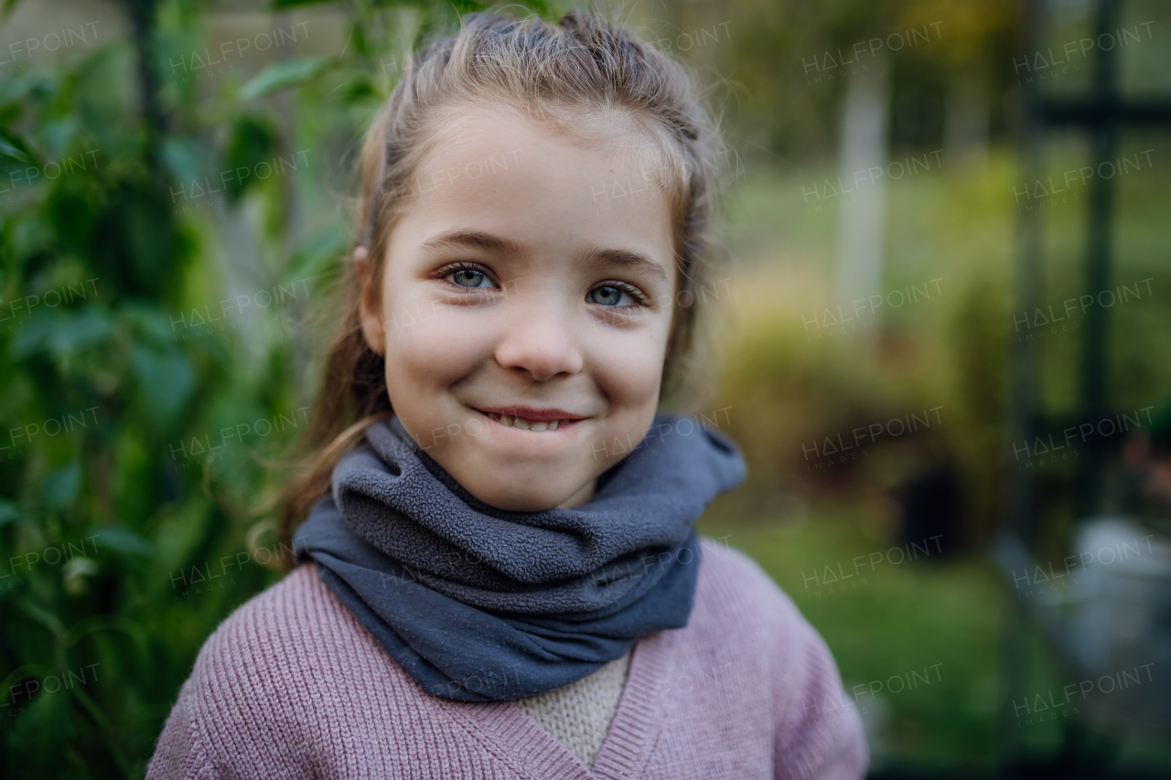 Portrait of little girl taking care of plants in garden, during first spring days, last autumn days. Concept of water conservation in garden and family gardening.