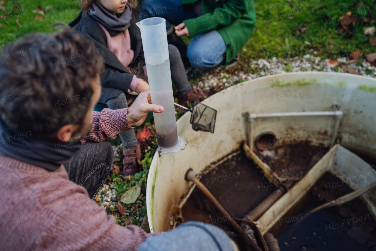 The family checks the water quality in the home wastewater or sewage treatment system. Concept of sustainable family living.