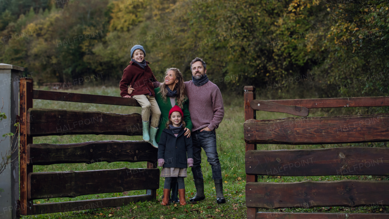 Portrait of family outdoors taking care of home garden. Mother, father and kids spending time outdoors during a cold autumn day.