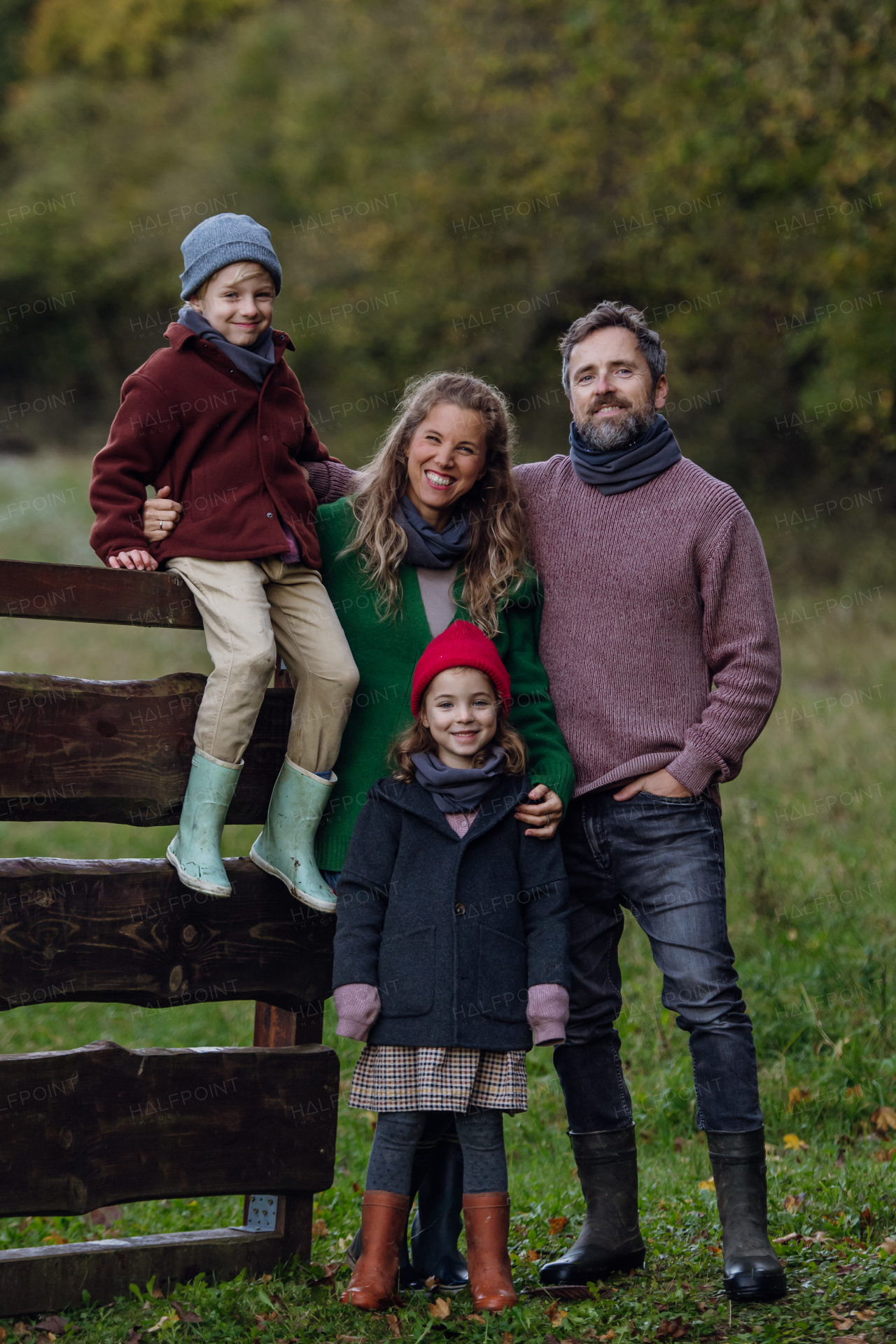 Portrait of family outdoors going on walk in nature. Mother, father and kids spending time outdoors during a cold autumn day.