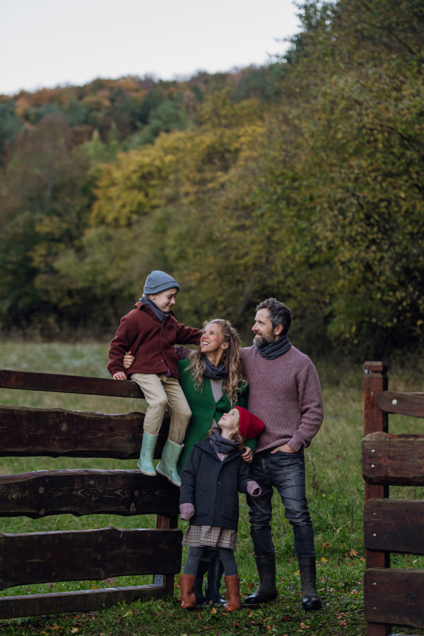 Portrait of family outdoors going on walk in nature. Mother, father and kids spending time outdoors during a cold autumn day.