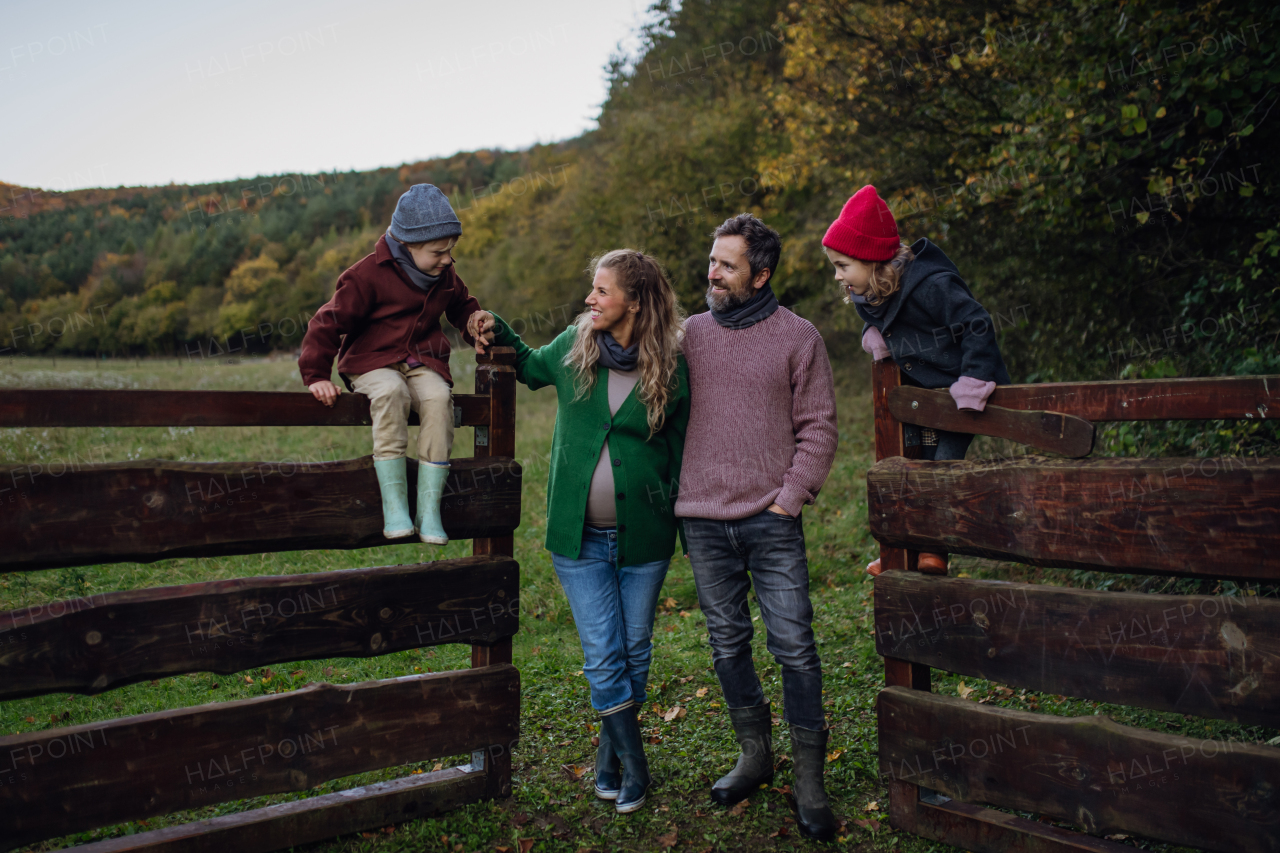 Portrait of family outdoors going on walk in nature. Mother, father and kids spending time outdoors during a cold autumn day.