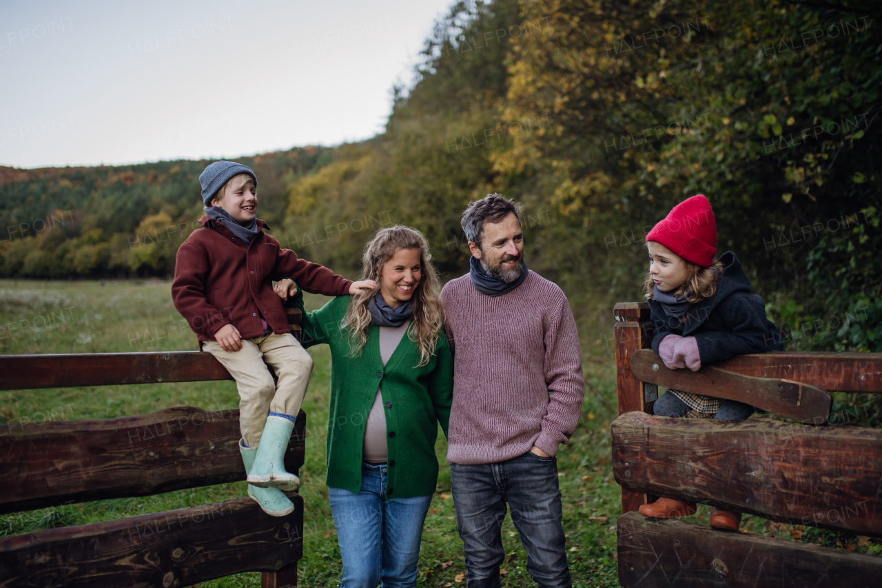 Portrait of family outdoors going on walk in nature. Mother, father and kids spending time outdoors during a cold autumn day.