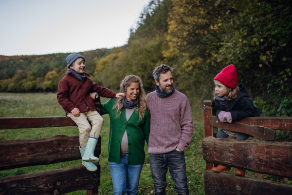 Portrait of family outdoors going on walk in nature. Mother, father and kids spending time outdoors during a cold autumn day.