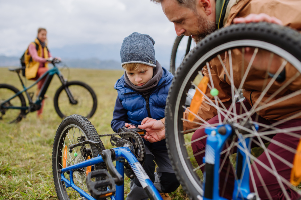 Young family with little children preparing for bicycle ride in nature. Concept of healthy lifestyle and moving activity.