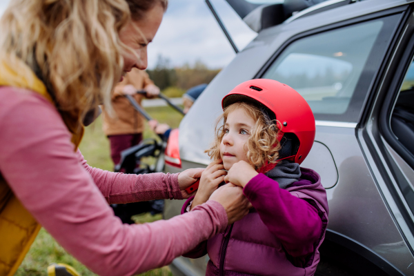 Young family with little children preparing for bicycle ride in nature, putting off bicycles from car racks. Concept of healthy lifestyle and moving activity.