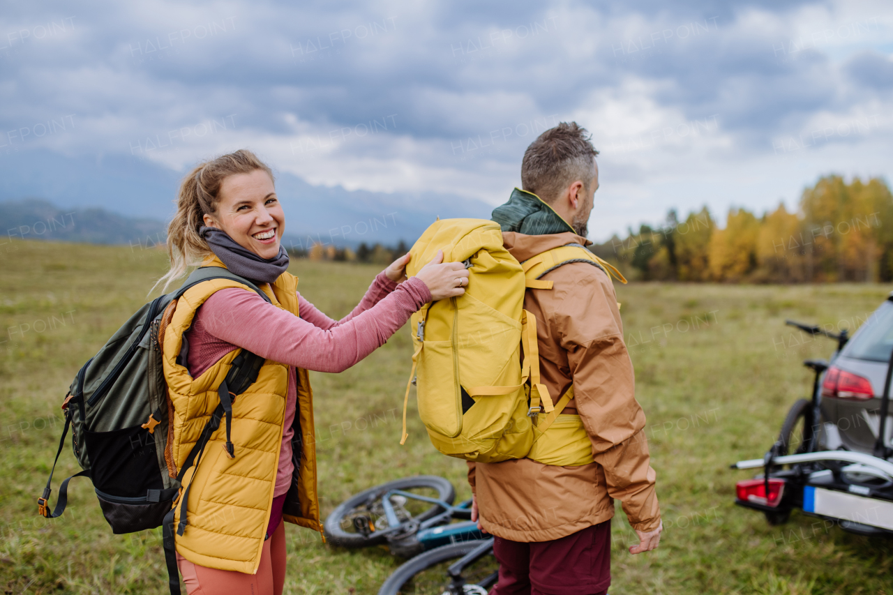 Happy couple preparing for bicycle ride in nature, in the middle of autumn nature. Concept of a healthy lifestyle.