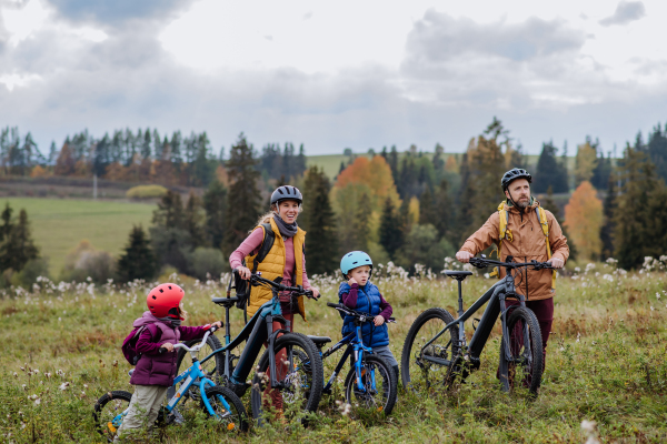 Young family with little children at bicycles, in the middle of autumn nature.Concept of healthy lifestyle.