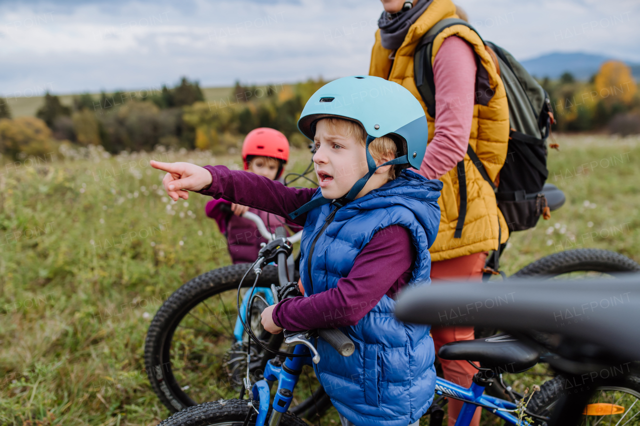 Portrait of little boy preparing for bicycle ride in nature. Cute boy pointing on something in the distance with finger.