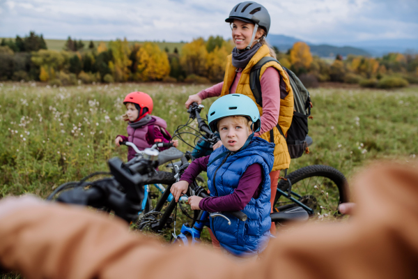 Young family with little children preparing for bicycle ride in nature. Concept of healthy lifestyle and moving activity.