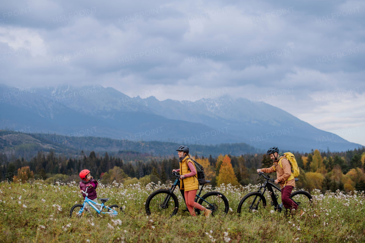 Young family with little daughter at bicycles, in the middle of autumn nature.Concept of healthy lifestyle.