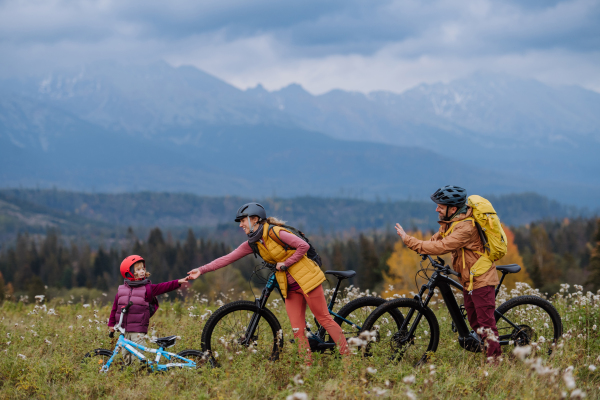 Young family with little daughter at bicycles, in the middle of autumn nature.Concept of healthy lifestyle.