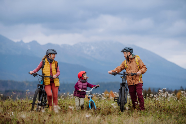 Young family with little daughter at bicycles, in the middle of autumn nature.Concept of healthy lifestyle.