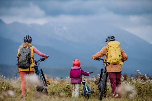 Rear view of family with little child at bicycles, in the middle of autumn nature.Concept of healthy lifestyle.