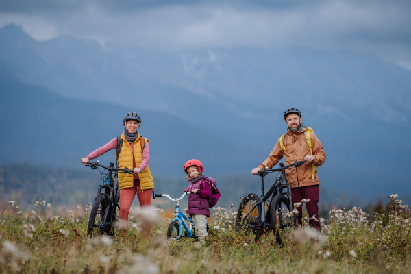 Young family with little daughter at bicycles, in the middle of autumn nature.Concept of healthy lifestyle.