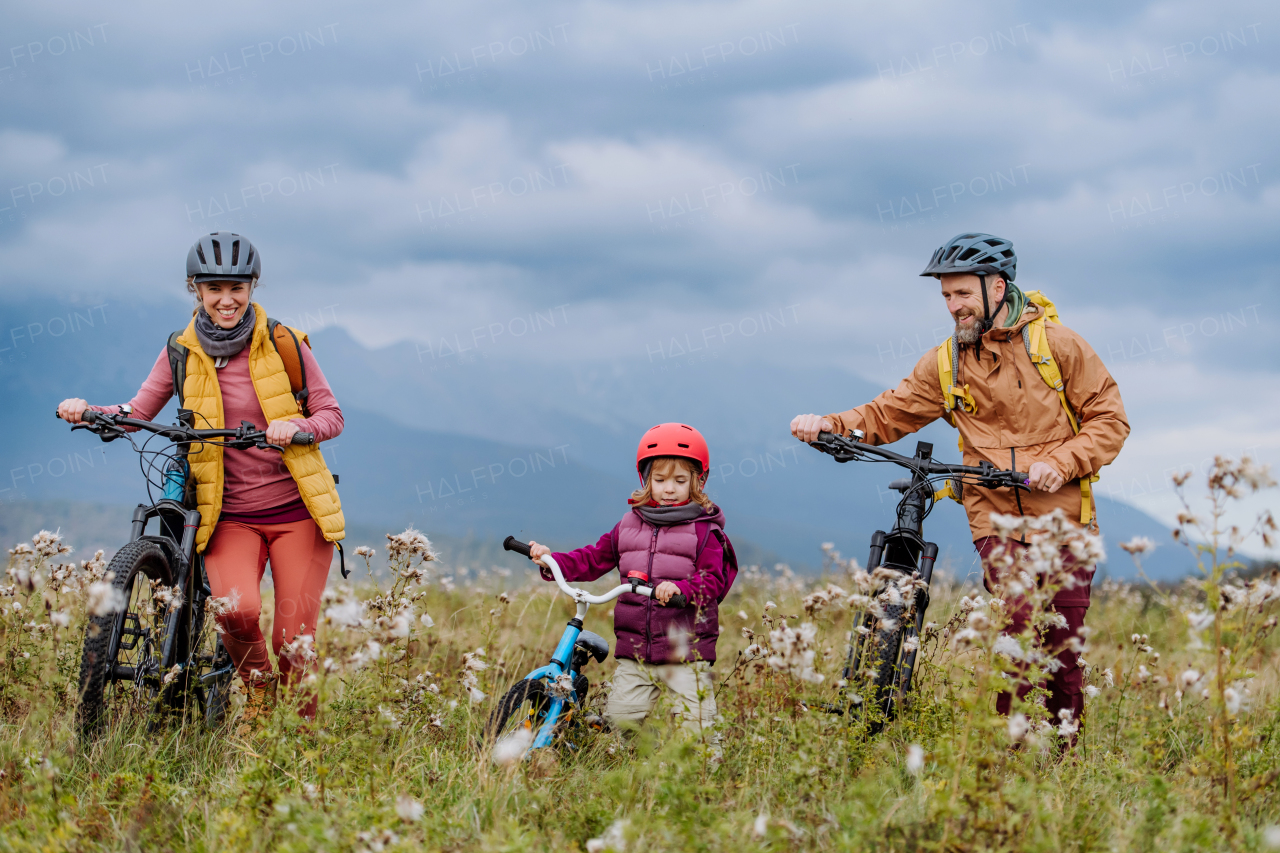 Young family with little daughter at bicycles, in the middle of autumn nature.Concept of healthy lifestyle.