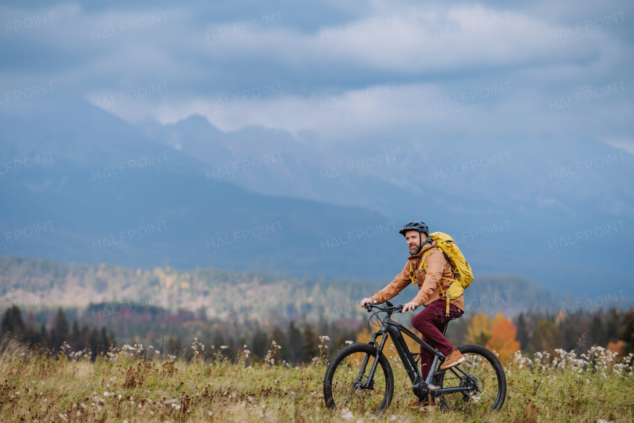 Active man on bike in the middle of autumn nature, admire mountains. Concept of healthy lifestyle.