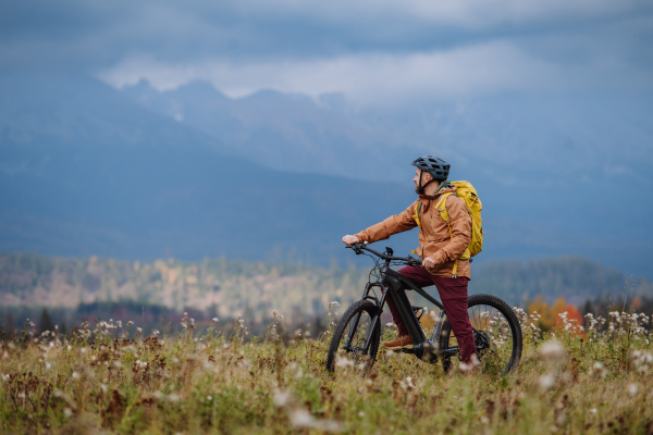 Active man on bike in the middle of autumn nature, admire mountains. Concept of healthy lifestyle.