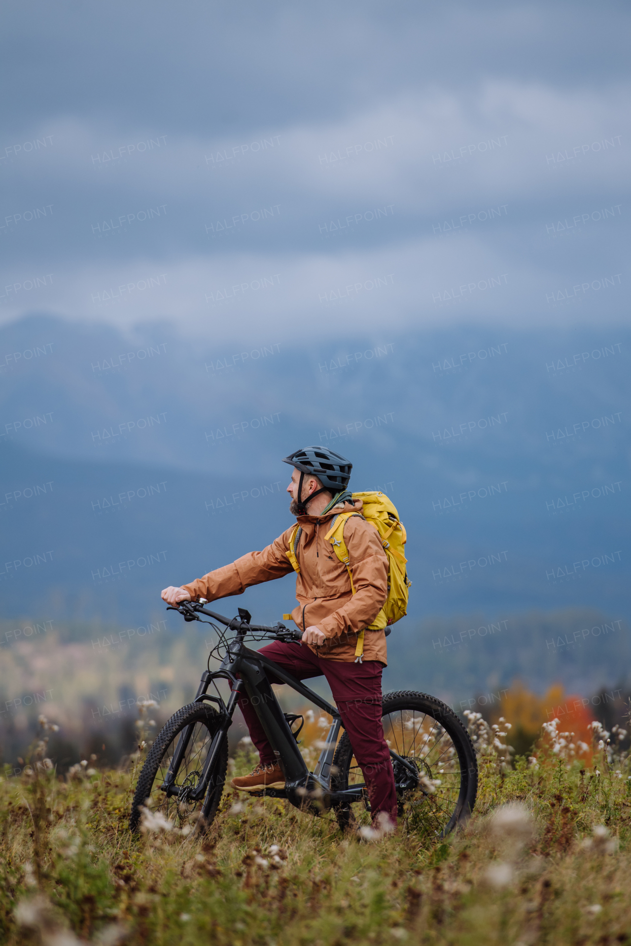 Active man on bike in the middle of autumn nature, admire mountains. Concept of healthy lifestyle.