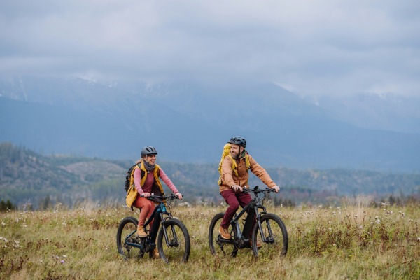 Yung happy couple at bicycles, in the middle of autumn nature. Married couple spending their honeymoons hiking, backpacking, visiting national parks.