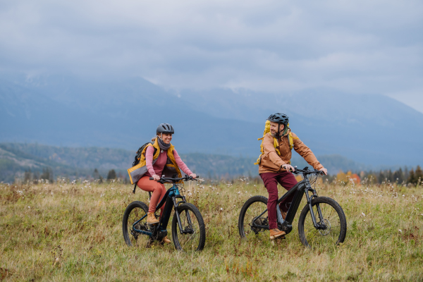 Yung happy couple at bicycles, in the middle of autumn nature. Married couple spending their honeymoons hiking, backpacking, visiting national parks.